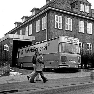 Bad Oldesloe: Bücherbus auf der Einfahrt in Anbau an gewerbliche Berufsschule: mittig im Bild 2 Fußgänger, im Vordergrund eine Straße