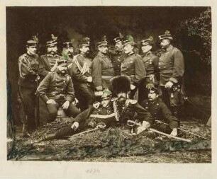 Gruppenbild: Adolf von Starkloff, General, mit zwölf seiner Stabsoffiziere der II. Feldbrigade vor Waldkulisse in Fotoatelier, in Uniform und Mütze, teils stehend, teils sitzend
