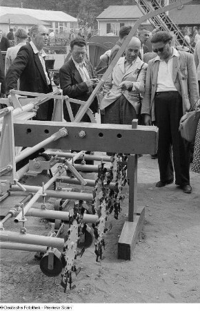 Ausstellungsbesucher an einem landwirtschaftlichen Gerät