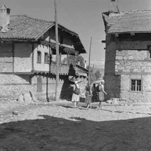 Alltagsbild. Frauen unterwegs in Bansko. Gestelle für das Trocknen der Tabakblätter am Wohnhaus in Bansko