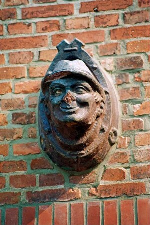 Fritz-Berodt-Straße 7-9: Hofanlage: östliches Wirtschaftsgebäude: Giebelseite, Detailaufnahme über Scheunentor: Fassadenplastik Kopf von Bauer: 19. August 1993
