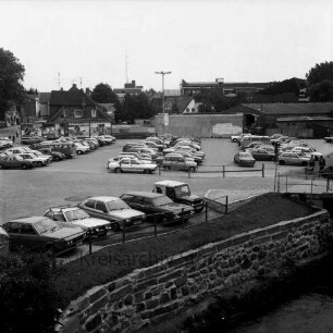 Parkplatz Heiligengeiststraße: parkende Pkw, vorne die Trave, mittig verläuft die Heiligengeiststraße, Blick Richtung Osten