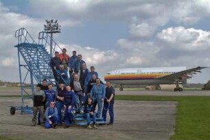 Air Maintenance Services; AMS; Firma; Betrieb; Inspektion; Wartung; spezialisiert auf Flugzeug-Recycling; Airbus; A 300; A300; Airbase Ahlhorn; Ahlhorn; Entsorgung. Ahlhorn, 2006, hier: die AMS-Belegschaft auf dem Rollfeld, auf einer Rolltreppe, im Hintergrund ein halber Airbus