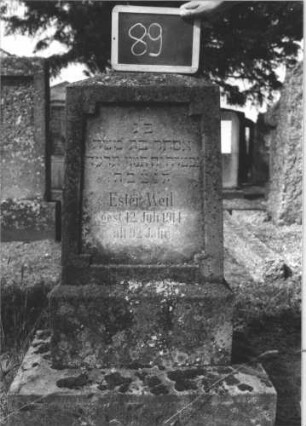 Grabstein 89 (Index: 100114088) Material: Sandstein Zustand: verwittert Maße HxBxT: 120x44x25 cm Beschreibung: Stele, getreppter Sockel, obeliskenartiger Abschluß, Schriftfeld rechteckig mit eingezogenen Ecken: Grabstein 89