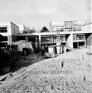 Emil-von-Behring-Gymnasium: Sieker Landstraße: III. Bauabschnitt: Schulgebäude vor Fertigstellung: vorn Erdhaufen und Sandhaufen sowie Baumaterial: hinten links Mann: hinten Mitte an Schulgebäude angelehnte Leiter