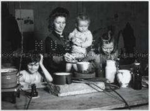 Mutter mit ihren Kindern bei der Zubereitung einer Mahlzeit auf einer provisorischen Kochstelle