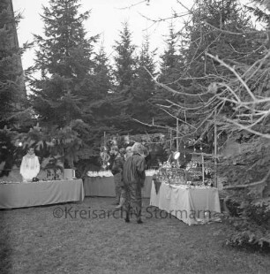 Rethwischdorf: Grundstück des stellvertretenden Kreispräsidenten Ernst Eick: Weihnachtsmarkt: vorn Marktstände mit Besuchern: dahinter Tannenreihe: im Hintergrund links Turm der Christuskirche