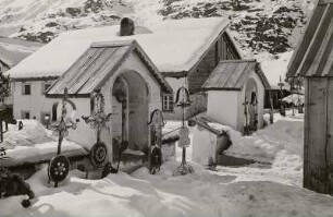 Obergurgl. Friedhof. Tiefverschneite Gräber mit eisernen Grabkreuzen am Friedhofseingang