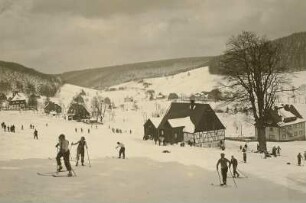 Rehefeld. Ortsteilansicht von Süden mit Blick in das Tal der Wilden Weißeritz abwärts. Im Vordergrund Skiläufer