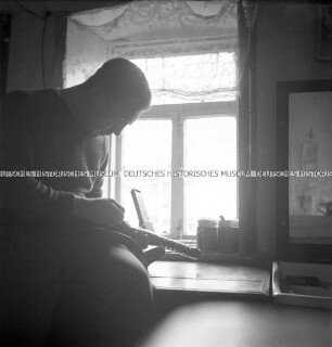 Hermann Hirchenhein beim Laden oder Reinigen seines Gewehrs am Fenster