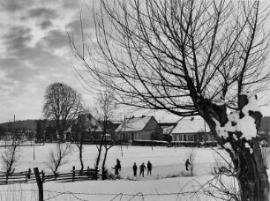 Reinbek im Winter. Kinder laufen auf dem zugefrorenen Mühlenteich Schlittschuh