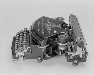 Stoßstangenschreibmaschine "Adler" (Modell 7). Vorderanschlag (sofort sichtbare Schrift), 30 Tasten, doppelte Umschaltung, Farbband. Seitenansicht von rechts oben : Stoßstangenschreibmaschine "Adler" (Modell 7). Vorderanschlag (sofort sichtbare Schrift), 30 Tasten, doppelte Umschaltung, Farbband. Seitenansicht von rechts oben. Baujahr: 1899 oder 1900; Hersteller: Adlerwerke vormals Heinrich Kleyer AG Frankfurt (Main); Verwalter: Sächsische Landesbibliothek - Staats- und Universitätsbibliothek Dresden (SLUB), Stenografische Sammlung, Inventar-Nummer R i 0001
