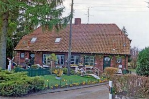 Blumendorf 4: traufständige Doppelkate aus Backstein: Straßenfront: Eingangstüren, Hausnummer, Sprossenfenster: Vorgärten, Baum, Strommast, Zäune, Hecken: vorne Einfahrt: 29. April 2003