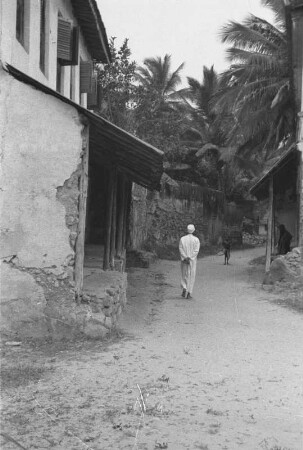 Mann in Bagamoyo : Ein Mann geht einen Weg zwischen den Häusern von Bagamoyo entlang.