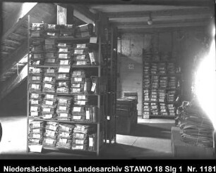 Braunschweigisches Landeshauptarchiv/Niedersächsisches Staatsarchiv in der Alten Kanzlei, Wolfenbüttel [um 1950] Enthält: Bodenraum mit gestapelten Aktenpaketen und Paketen in Regalen
