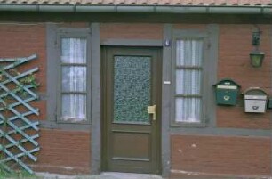 Vorburgstraße 6: traufständige Zweifamilien-Fachwerkkate: Straßenfront: Teilansicht: Eingangstür, beiderseits schmale Sprossenfenster