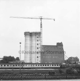 Johannes Ströh Mühlenwerke: Lagerstraße [später Johannes-Ströh-Straße]: Bau eines Betonsilos: Blick von der Mommsenstraße über das Bahnhofsgelände mit Personenzug: rechts Backsteinsilo: davor Baukran: 11. Juni 1972
