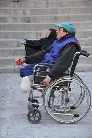 Barcelona - Behinderter im Rollstuhl bettelt : Vor der Kathedrale sitzt ein behinderter Mann in seinem Rollstuhl und bettelt Passanten an. Aufgenommen am 15. April 2012 in Barcelona