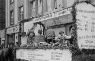 Jugendliche beim handwerklichen Arbeiten auf einem von Pferden gezogenen Wagen während eines Umzugs anlässlich der Festtage des Handwerks