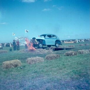 Holland. Autocrossveranstaltung. Ein Auto fährt auf der Rennstrecke über eine Sprungschanze, unter der ein Feuer brennt