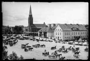 Ortelsburg (Szczytno/Polen). Marktplatz mit Katholischer Kirche, Marktständen und Pferdefuhrwerken