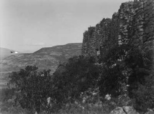 Steinmauer : Reste einer Steinmauer, im Hintergrund eine Hügellandschaft.
