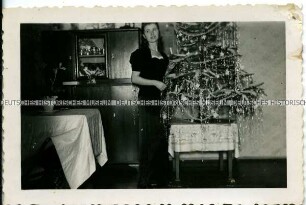 Junge Frau im Abendkleid neben dem Weihnachtsbaum