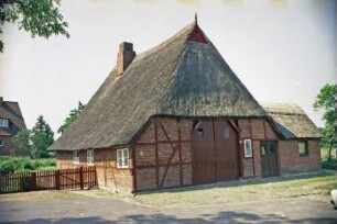 Alte Dorfstraße 50: Fachwerkkate mit Reetdach: Giebelseite Wirtschaftstrakt mit Scheunentor und seitlichem Anbau: links Traufseite