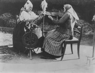Spinnrad : Zwei Frauen spinnen Flachs
