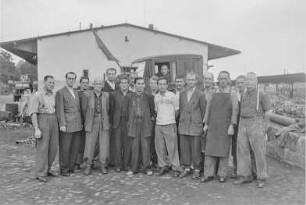 RHZ Schrott Bahnhof : Gruppenaufnahme von Arbeitern vor einem Bahnhof