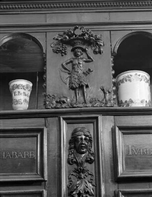 Regalwand aus der ehemaligen Charité-Apotheke in Lyon — exotische Figur (Indianer?) mit Früchtekorb auf dem Haupt