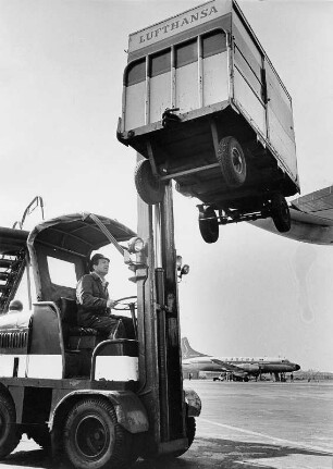 Hamburg. Der Flughafen Fuhlsbüttel. Ein Gepäckwagen der Lufthansa wird in ein Flugzeug mittels Stapler verladen. Im Hintergrund steht ein Flugzeug der belgischen Airline "Sabena" auf dem Rollfeld. Aufgenommen 1957