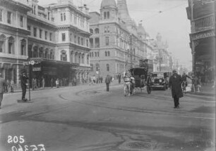 Straße in Kapstadt : Straßenszene an einer Kreuzung mit herrschaftlichen Stadthäusern, Automobilen und Pferdekutsche
