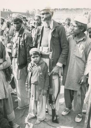 Mudschahedinkämpfer mit Kind : Mudschahedin-Kämpfer mit Kind in einem afghanischen Flüchtlingslager in Pakistan, aufgenommen im Oktober 1987