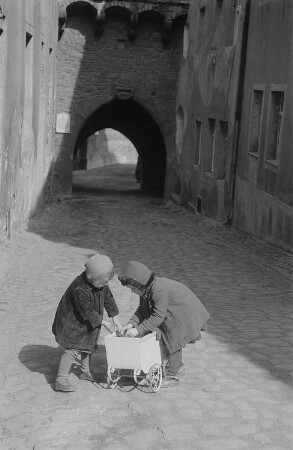 Zwei kleine spielende Mädchen mit einem Puppenwagen