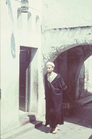 Reisefotos. Straßenbild mit Mann in schwarzem Kaftan (vielleicht in Algier)