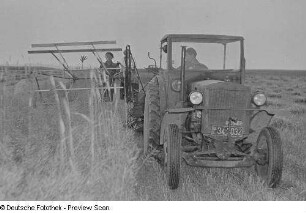 Landwirte beim Mähen von Getreide mit Hilfe eines Traktors und einer Mähmaschine