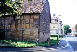 verfallendes Bauernhaus, hinten alte Dorfschule