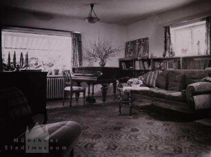 München-Grünwald. Wohnzimmer mit Bibliothek, Klavier und großem Blumenfenster