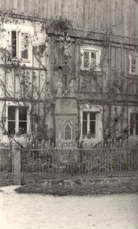 Wohnhaus mit Keuzdenkmal im Vorgarten in Panschwitz-Kuckau : Swjaty křiž w zahrodźe před domskim w Pančicach-Kukowje