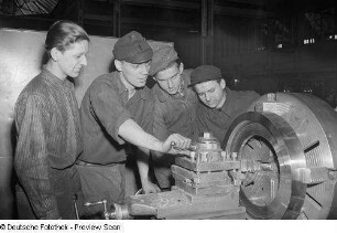 Vier junge Männer (einer IFA Getriebewerk Brigade?) an einer Maschine