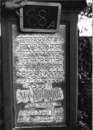 Grabstein 88 (Index: 100080559) Material: Sandstein, weiße Marmorplatte Zustand: leicht verwittert Maße HxBxT: 137x51x25 cm Beschreibung: profiliert. Sockel, Giebel m. stilisiert. Eckakroteren, rechteck. Schriftfeld eingetie Symbolik: Sternchen im Giebel, Blätter in den Akroteren: Grabstein 88A