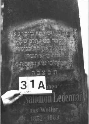 Grabstein 31 (Index: 99898743) Material: Sandstein Zustand: hebräische Inschrift völlig verwittert, deutsche Inschrift stark verwittert Maße HxBxT: 120x46x17 cm Beschreibung: aufgesockelte Stele mit Rundbogenabschluss, Sockel felsartig gearbeitet: Grabstein 31A