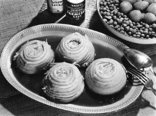 Krafts Rezeptaufnahmen. Nudelschnecke mit Soße. Daneben eine Dose Parmesan, eine Flasche Tomatenketchup und eine Schale mit Gemüse