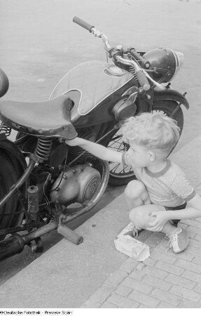 Kleiner Junge, an einem Motorrad spielend