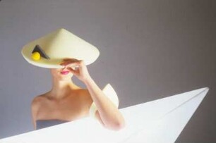 Model in Schaumstoffmode : Model mit gelbem Schaumstoffhut hinter einem Neonleuchtkörper