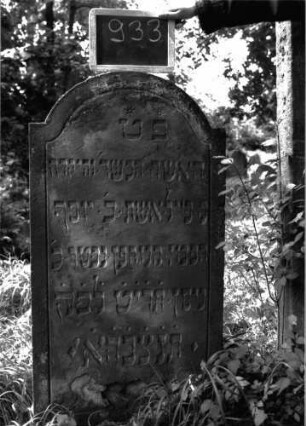 Grabstein 933 (Index: 100103821) Material: Sandstein Zustand: gut erhalten, unten beginnende Verwitterung Maße HxBxT: 118x58x10 cm Beschreibung: Stele, eingezogener Rundbogenabschluss, Schriftfeld mit Konvexbogenabschluss durch umlaufende Rille abgeteilt, sternförmiges Abkürzungszeichen über der 1. Zeile: Grabstein 933