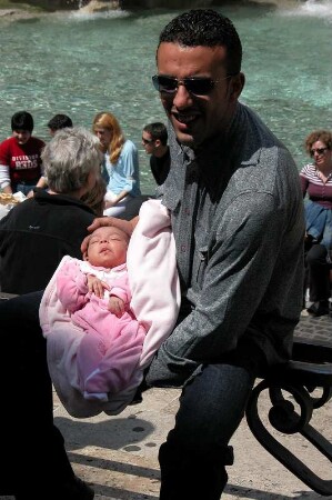 Rom - Mann mit Baby am Trevibrunnen : Touristen am Trevi-Brunnen in Rom, aufgenommen im April 2004