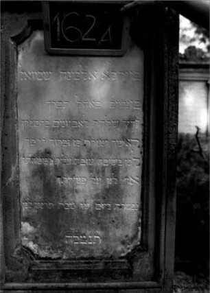 Grabstein 162 (Index: 100109743) Material: Sandstein, weiße Marmorplatte Zustand: Sockel leicht verwittert Maße HxBxT: 156x60x34 cm Beschreibung: rechteckige Stele, getreppter Sockel, Schriftplatte mit eingezogenen Ecken: Grabstein 162A