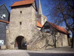 Ansicht von Südwesten mit Torturm (veränderte Schießscharten in den Obergeschossen) sowie anschließender Kirchhofmauer in Übersicht